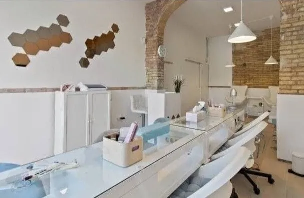 Interior de Cloud Nails: mesas de manicura blancas con cojines celestes y sillones de pedicura al fondo